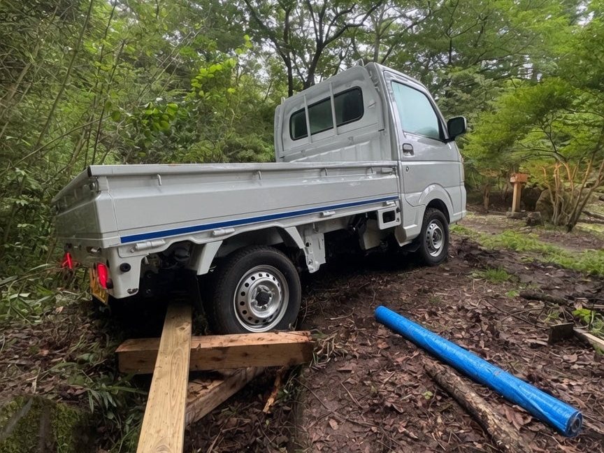軽トラックと給水用の配管を運び込み、水の確保と滞在設備を整えている様子